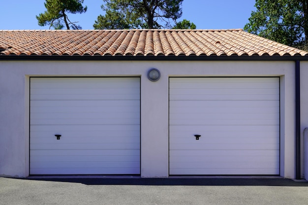 O portão seccional duplo da garagem fechou duas portas brancas em casa residencial privada