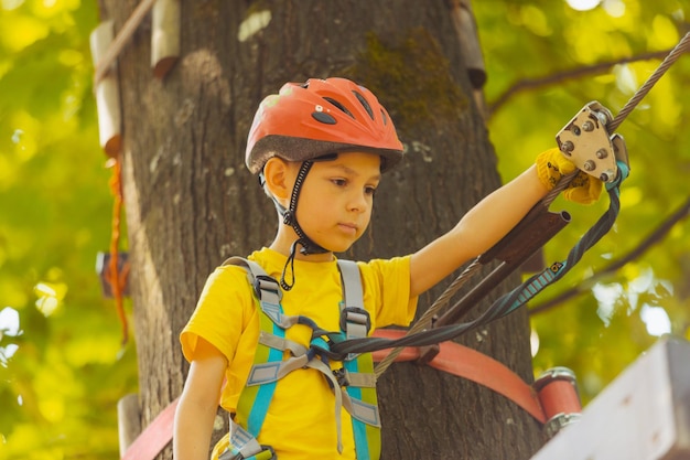 O pré-escolar fofo está brincando no parque de aventura