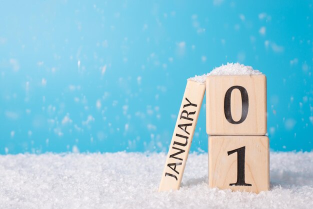 O primeiro dia de um novo conceito de ano. feche a foto do calendário de cubos de madeira mostrando a data de um ano novo, isolada em um fundo azul com queda de neve