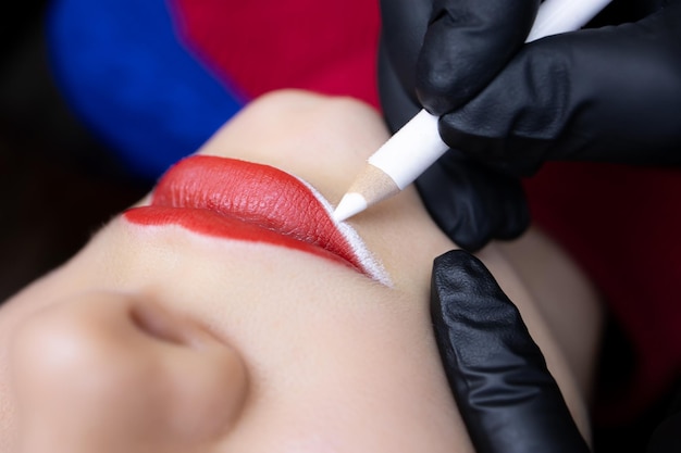 O procedimento de tatuagem labial permanente macro fotografia dos lábios do modelo no qual o mestre aplica o contorno antes do procedimento de tatuagem