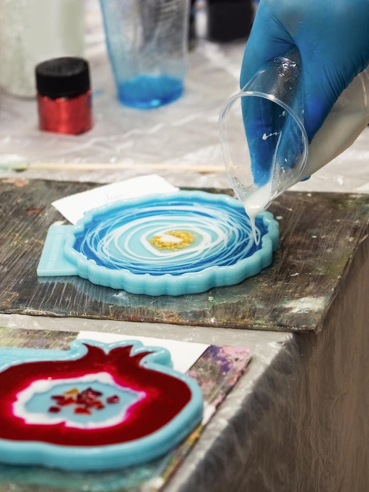 Foto o processo artístico de derramar resina epóxi em um brinquedo de madeira. processo de tecnologia de criação de uma pintura em resina de estilo art, trabalha com epóxi em estúdio, faz um suporte de madeira com a imagem. fechar-se.