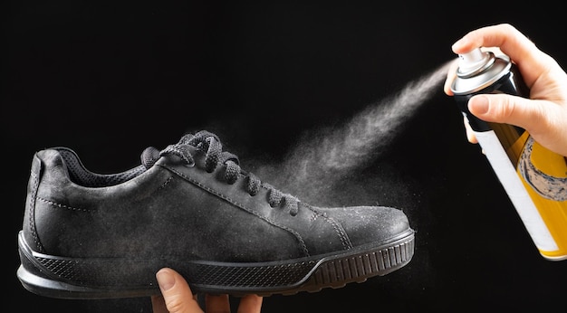 O processo de aplicação de um spray repelente de água em sapatos nobuck de meia estação masculinos negros