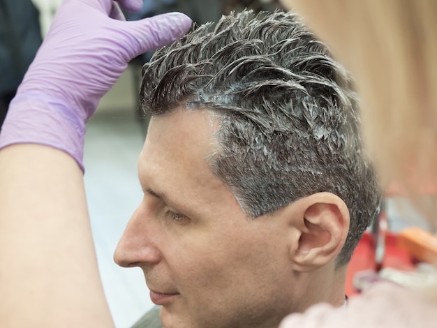 O processo de coloração do cabelo de um homem em um salão de beleza. fechar-se.