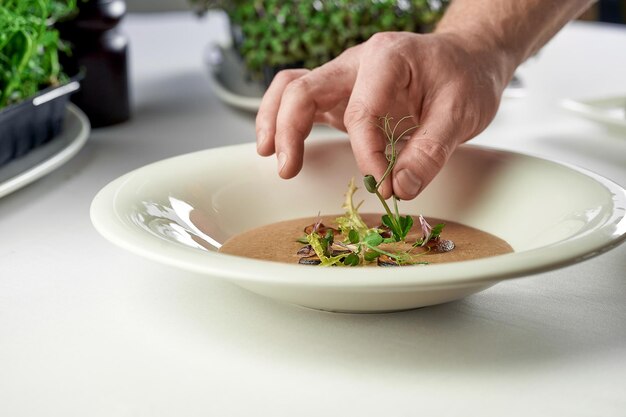 O processo de decoração da sopa de creme de cogumelos Chef coloca especiarias e cogumelos em um prato