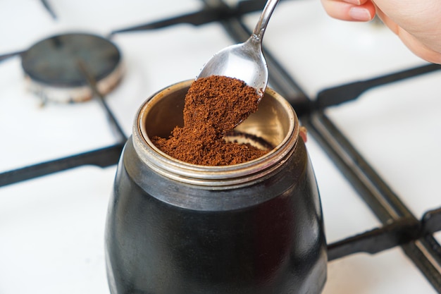 O processo de derramar café moído em uma cafeteira de gêiser