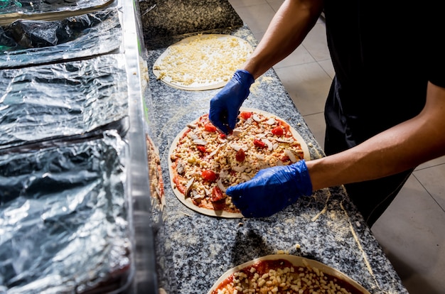 O processo de fazer pizza. Mãos do chef padeiro fazendo pizza na cozinha de café
