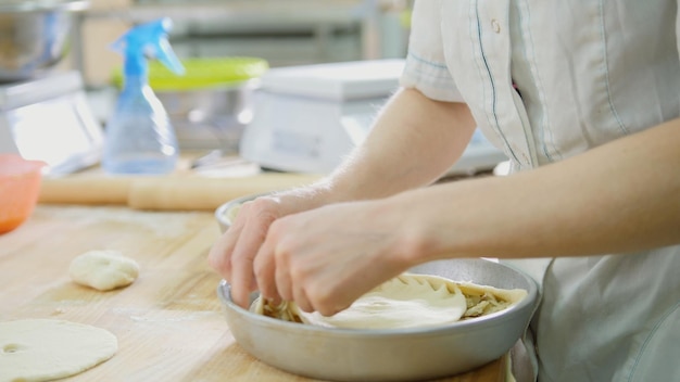 O processo de fazer tortas com as mãos - mulher na padaria, close-up