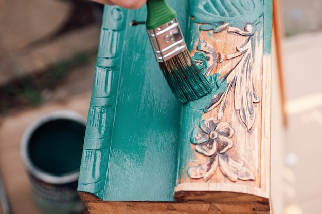 O processo de pintar uma gaveta de cômoda de madeira ou mesa com um padrão floral ao ar livre um amigo ecológico ...
