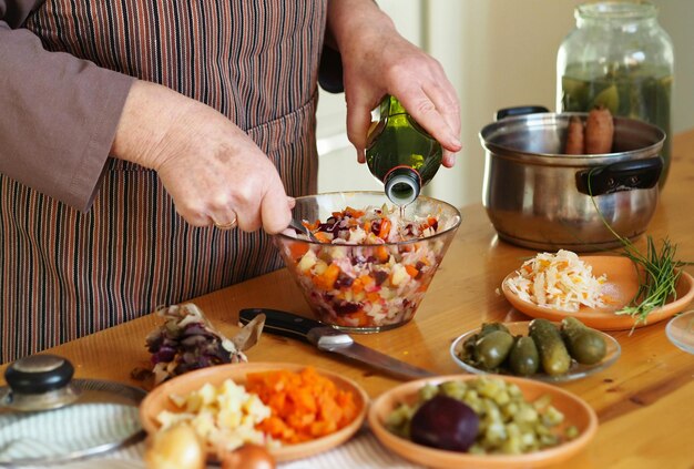 Foto o processo de preparação de uma salada de vinaigrette de beterraba e legumes cozidos para uma mulher idosa