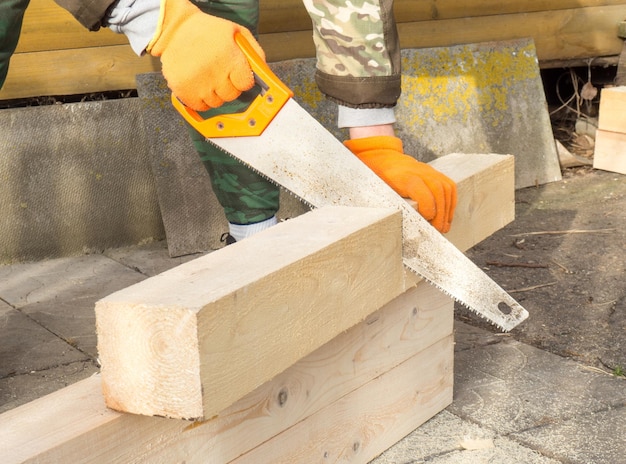 O processo de serragem manual de madeira um homem serrando uma madeira ao construir uma casa