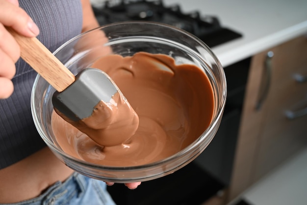 O processo de temperar chocolate e fazer chocolates Chef de pastelaria usando espátula temperando chocolate derretido