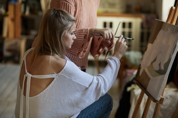 Foto o professor ensina uma jovem a pintar sobre tela