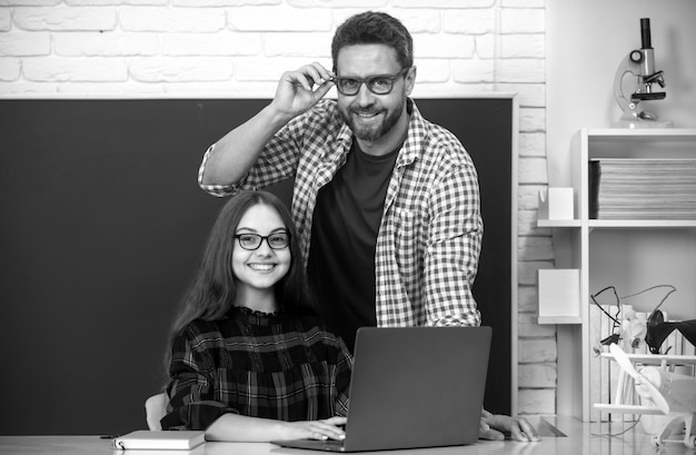 O professor tutor ajudando a criança na aula na escola usando o laptop