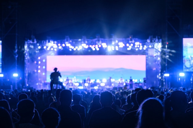 O público jovem de silhueta está assistindo o concerto noturno