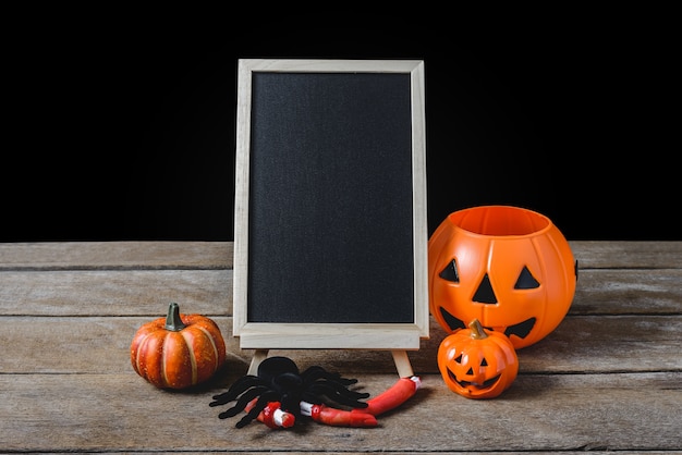 O quadro-negro no stand com abóboras de Halloween, aranha preta no piso de madeira