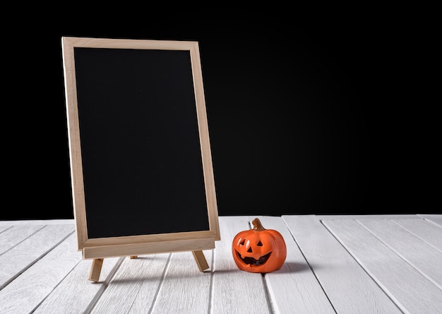 O quadro-negro no stand com halloween pumpkins no piso de madeira e fundo preto