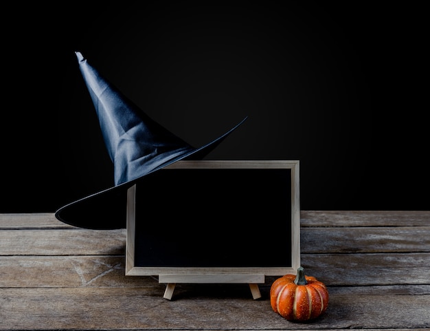 O quadro no stand, chapéu de bruxa com Halloween Pumpkins no piso de madeira