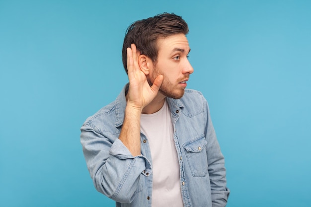 O que. Eu não posso ouvir. Retrato de homem de camisa jeans trabalhador segurando a mão perto da orelha e ouvindo com atenção, tendo problemas auditivos, surdez e mal-entendidos na comunicação. tiro de estúdio isolado