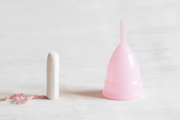 O que você escolhe um tampão ou copo menstrual Fundo vintage branco Foco seletivo luz do dia