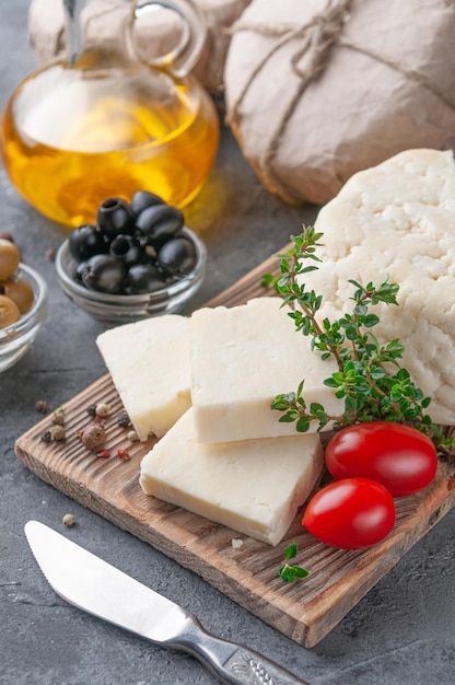 O queijo Adyghe é cortado em pedaços O queijo em uma placa de madeira