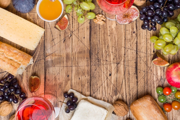 O queijo, o vinho, o baguette molham figos dos figos e petiscos no tampo da mesa de madeira rústico com espaço da cópia.