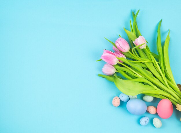 O ramalhete das tulipas e dos ovos da páscoa em um fundo azul copia o espaço.