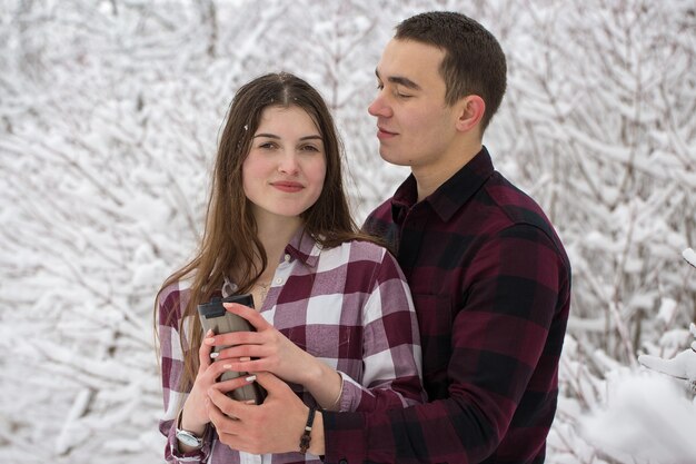 O rapaz e a rapariga descansam na floresta de inverno marido e mulher na neve casal jovem