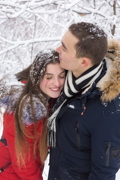 O rapaz e a rapariga descansam na floresta de inverno Marido e mulher na neve Casal jovem