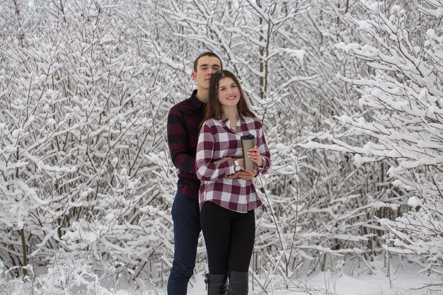 O rapaz e a rapariga descansam na floresta de inverno Marido e mulher na neve Casal jovem