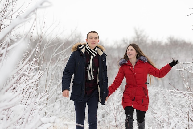 O rapaz e a rapariga descansam na floresta de inverno Marido e mulher na neve Casal jovem