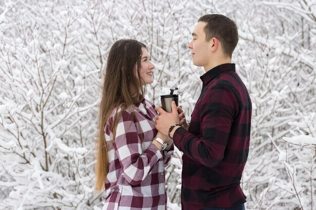 O rapaz e a rapariga descansam na floresta de inverno Marido e mulher na neve Casal jovem