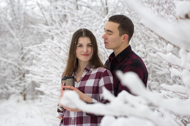 O rapaz e a rapariga descansam na floresta de inverno Marido e mulher na neve Casal jovem