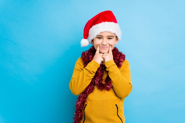 O rapaz pequeno que comemora o dia de natal que desgasta um chapéu de santa isolou a dúvida entre duas opções.