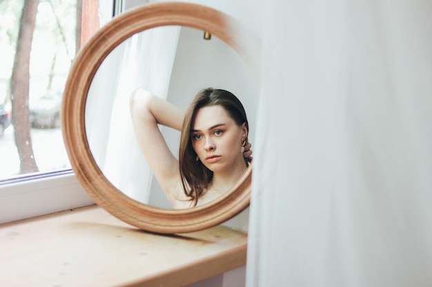 O reflexo de uma bela mulher no espelho em casa