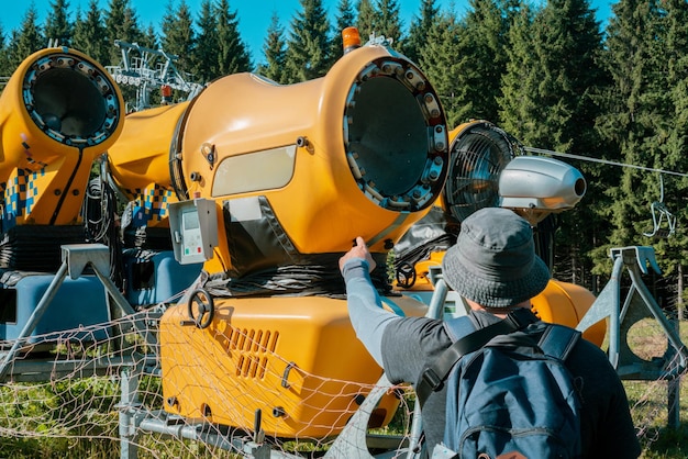 O reparador mostra o dedo em uma máquina de fazer neve na madeira Enorme dispositivo Control Check Nature Electricity Power