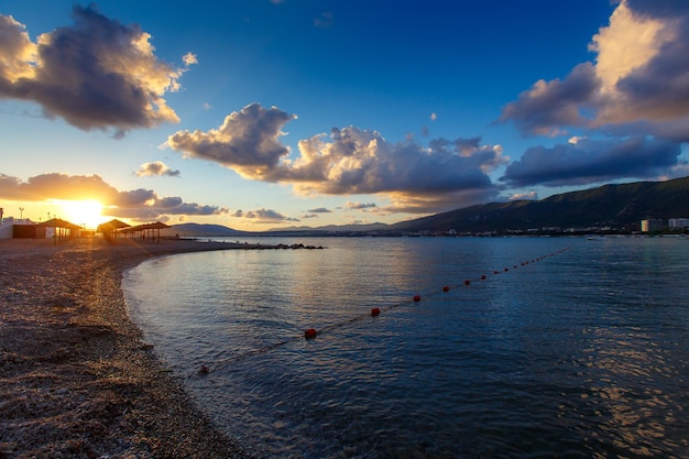 O resort de Gelendzhik Pôr do sol na baía de Gelendzhik Na praia de seixos em primeiro plano