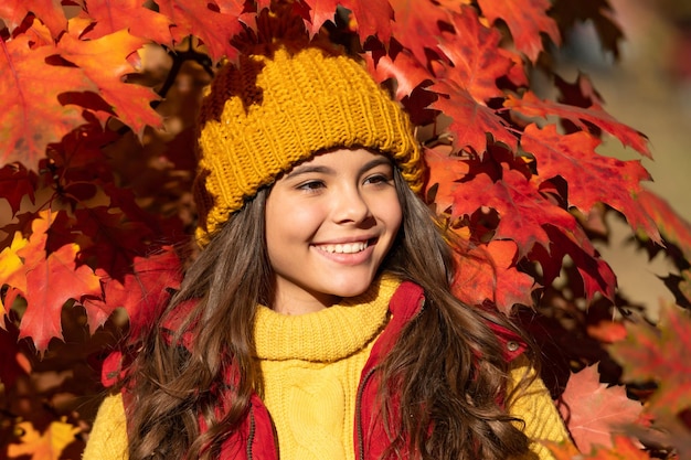 O retrato da menina adolescente do outono deixa o conceito de criança feliz no chapéu em pé nas folhas do outono