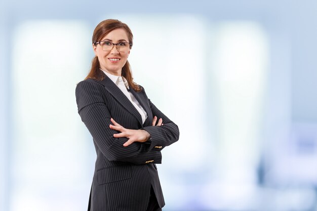 O retrato das orelhas bonitas de uma mulher de negócios 50 velhas nos braços cruzados levanta no escritório.