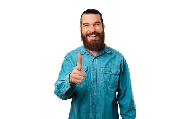 Foto o retrato de um homem barbudo alegre está apontando para você ou diretamente para a câmera