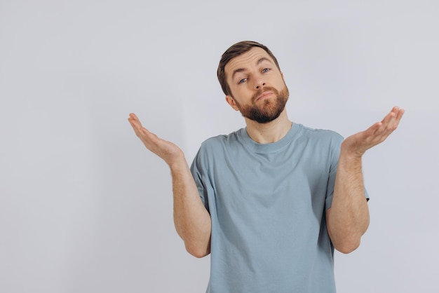 O retrato de um homem barbudo moderno de meia-idade em uma camiseta azul mostra que ele não conhece a emoção em um fundo branco