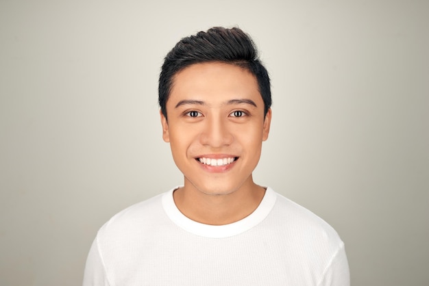 O retrato de um jovem asiático feliz e bonito está sorrindo em fundo branco