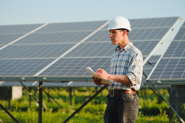 O retrato de um jovem engenheiro verifica painéis solares fotovoltaicos