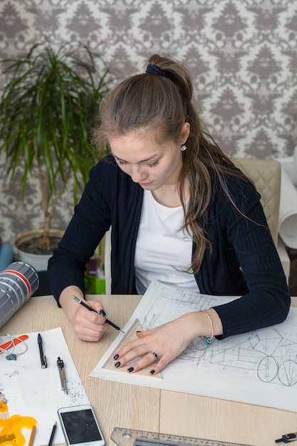 O retrato de um jovem estudante concentrado na mesa está envolvido no desenho do projeto arquitetônico