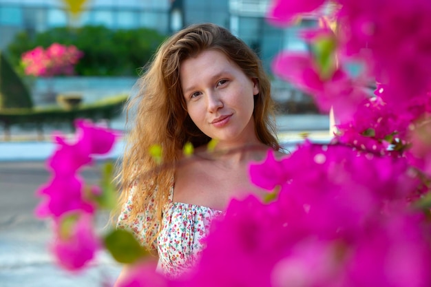 O retrato de uma linda e feliz jovem positiva está cheirando lindas flores cor-de-rosa no