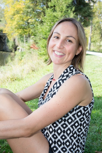 O retrato de uma mulher consideravelmente feliz senta-se no parque do jardim