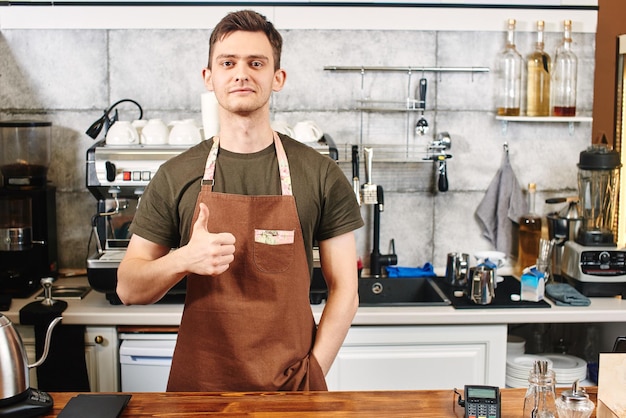 O retrato do cara baristas no local de trabalho no fundo do café