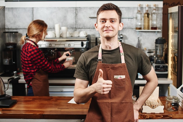 O retrato do cara baristas no local de trabalho no fundo do café