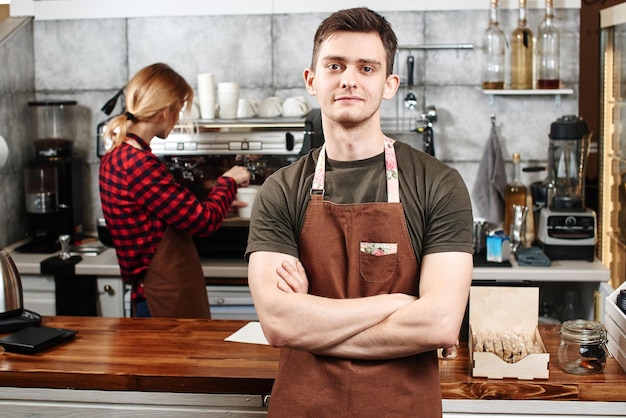 O retrato do cara baristas no local de trabalho no fundo do café