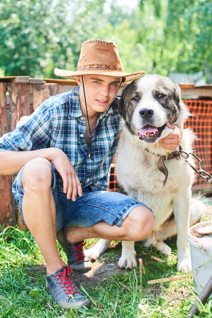 O retrato do cara de chapéu abraçando um cachorro na vila