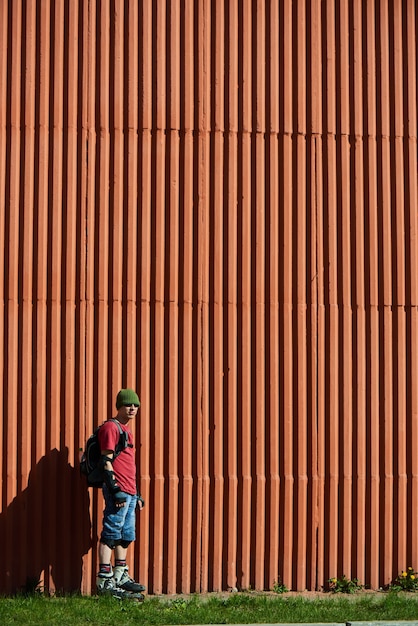 O retrato do cara nos rolos contra a parede vermelha